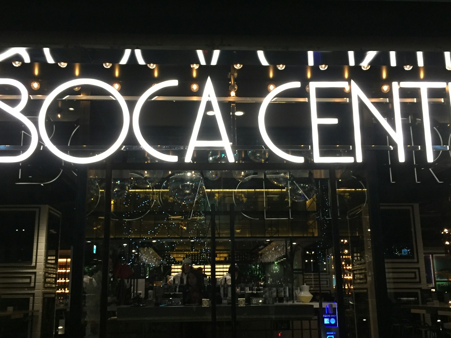 Insegna luminosa del Boca Center di notte con architettura moderna