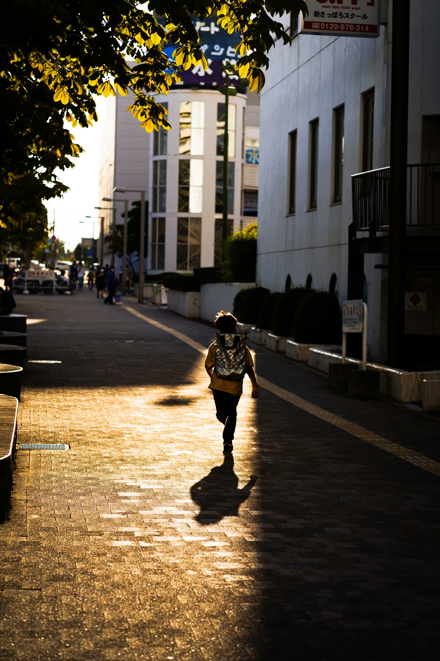 Silhouette of a person walking in a sunset-lit street with warm light contrast
