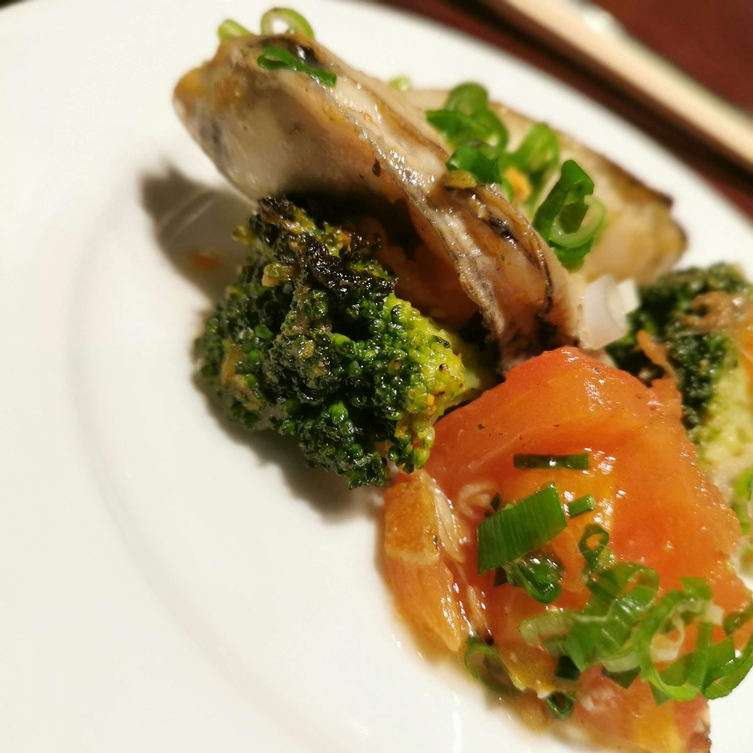 Grilled fish served with broccoli and tomato salad on a white plate
