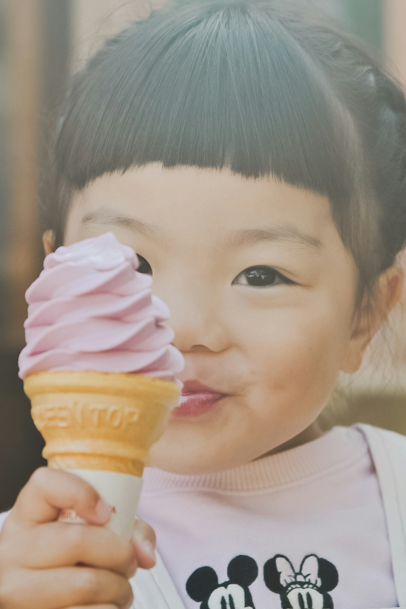 Seorang anak tersenyum memegang cone es krim ungu