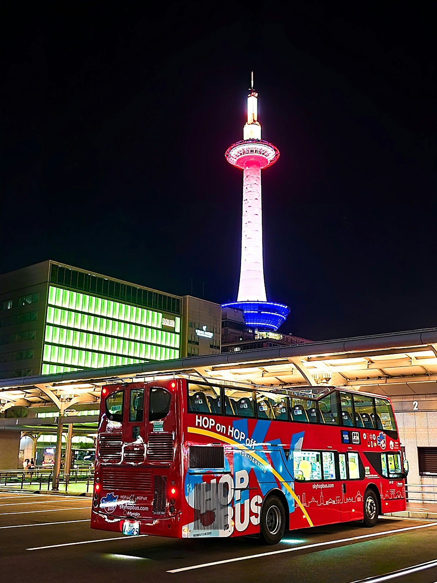 Night view of Kyoto Tower with a red sightseeing bus