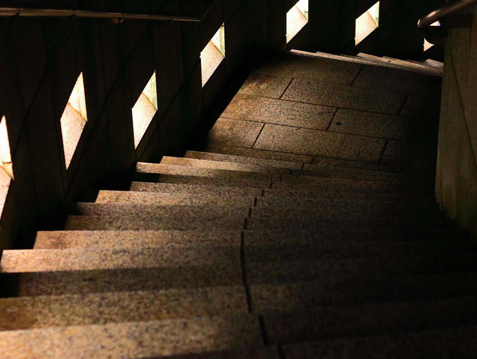 Dimly lit staircase with illuminated sections along the railing