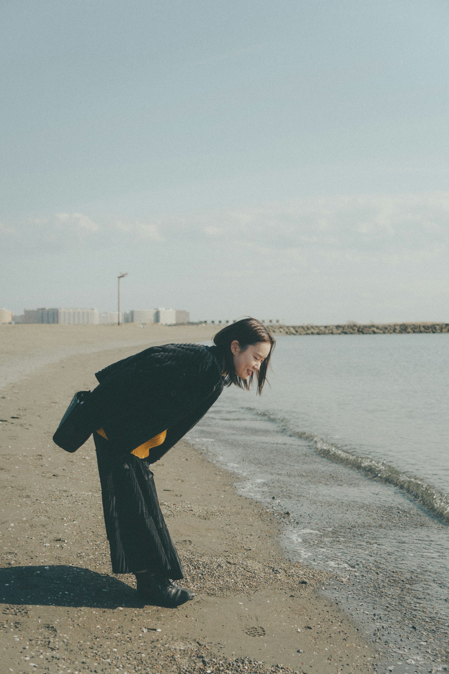 Frau beugt sich zum Wasser am Strand