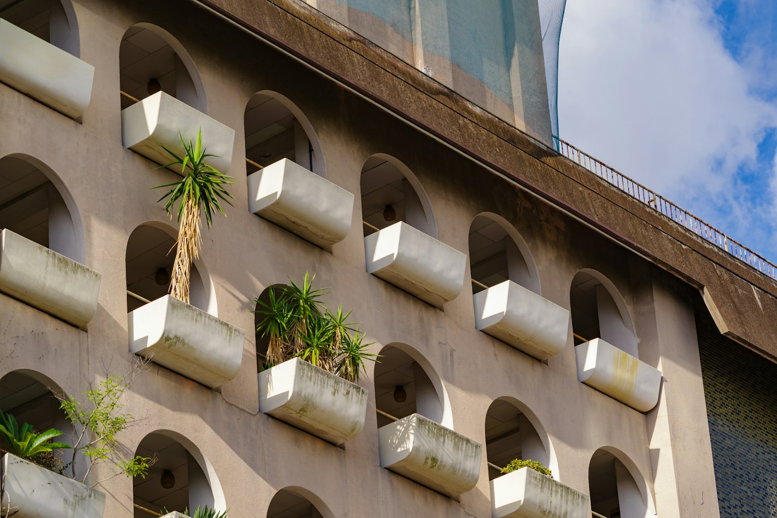 Facciata di un edificio con balconi ad arco e vasi contenenti piante