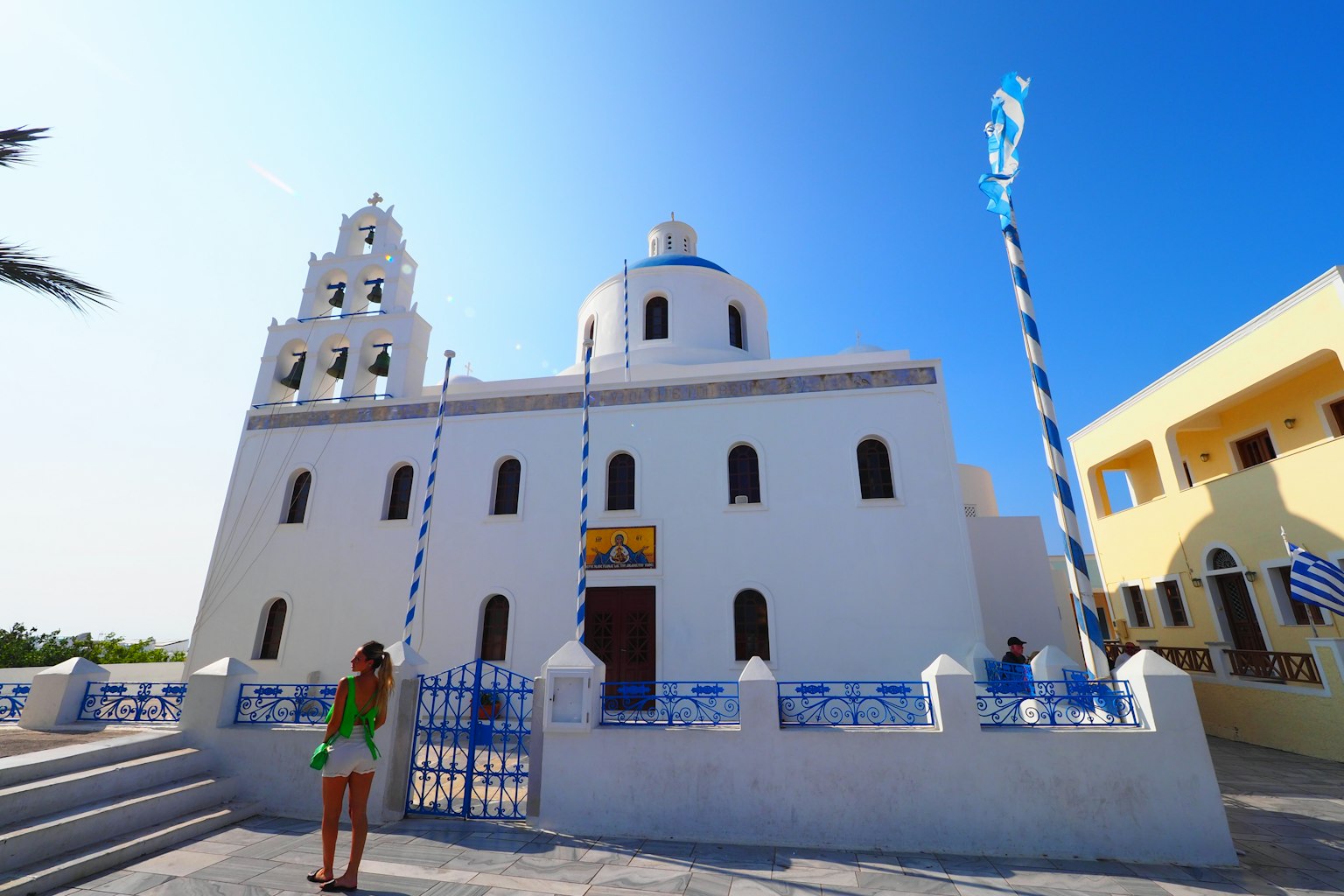 Weiße Kirche mit blauer Kuppel unter klarem Himmel mit einer Frau