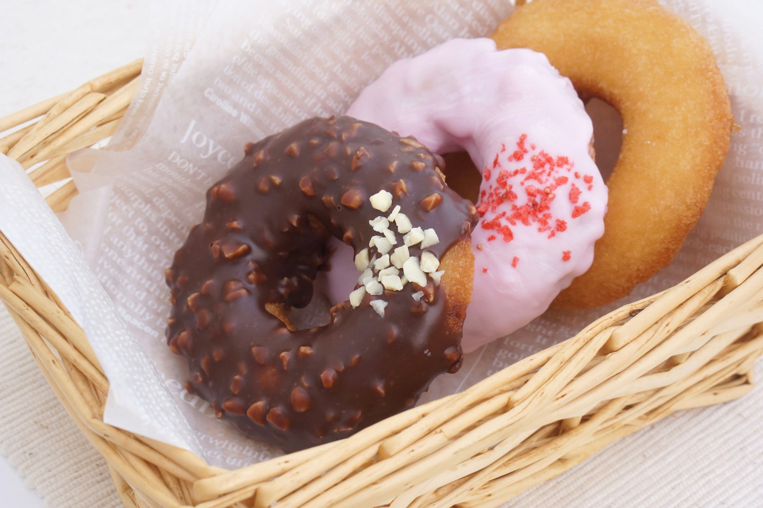 Drei Arten von Donuts in einem Korb mit Schokoladenglasur rosa Glasur und natur
