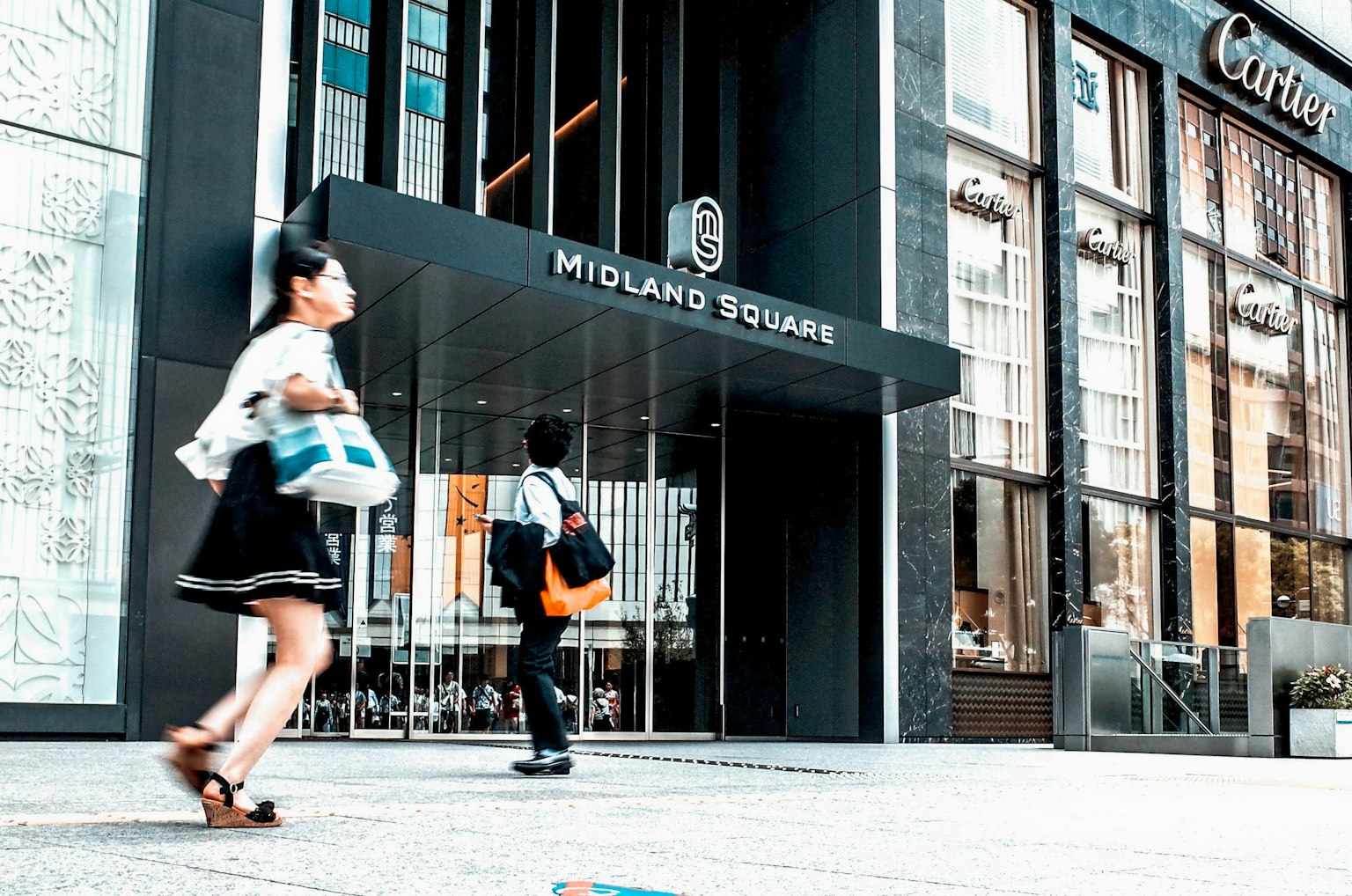 Menschen, die vor dem Eingang von Midland Square mit Einkaufstaschen gehen