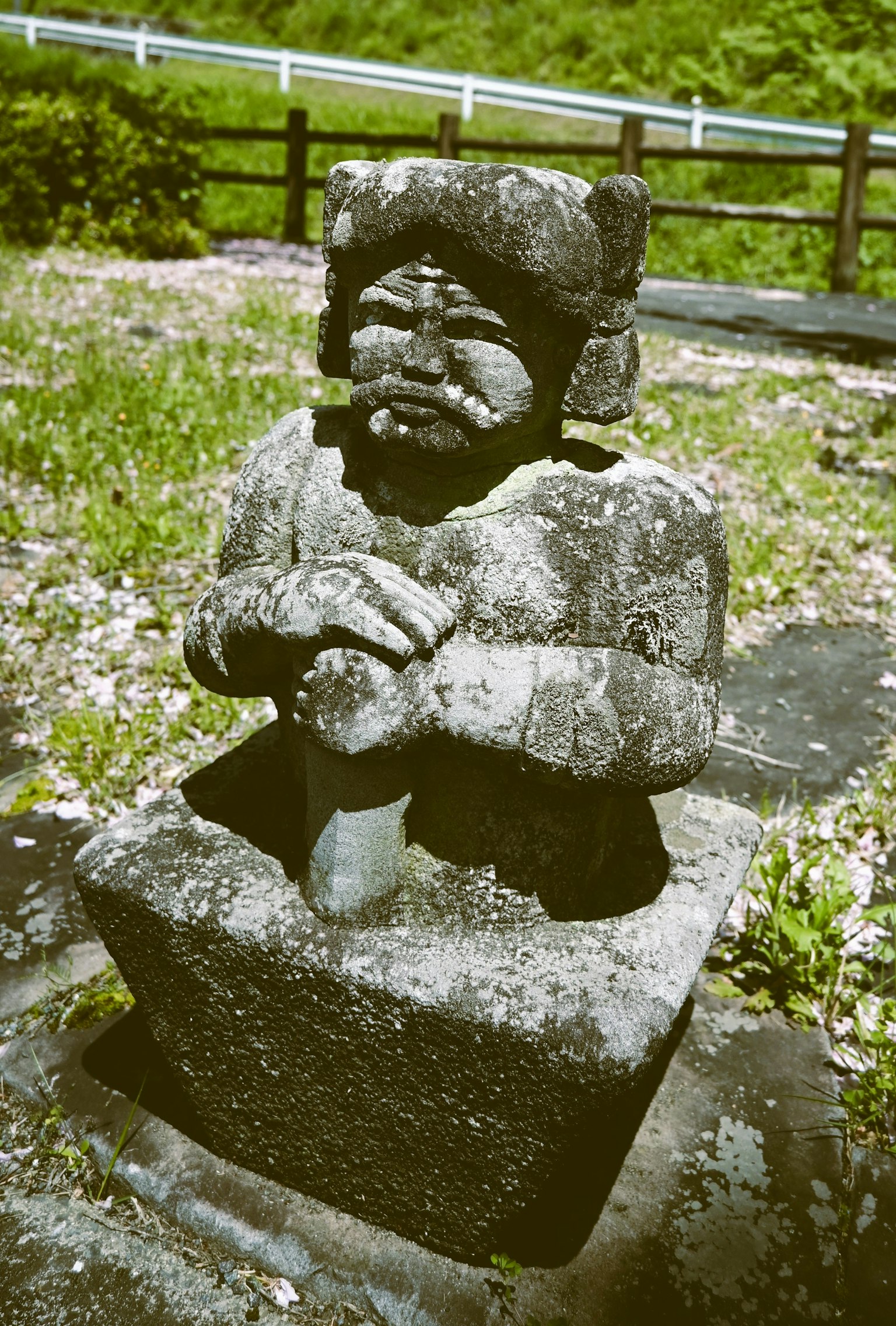 Una statua di pietra antica si trova su un terreno erboso