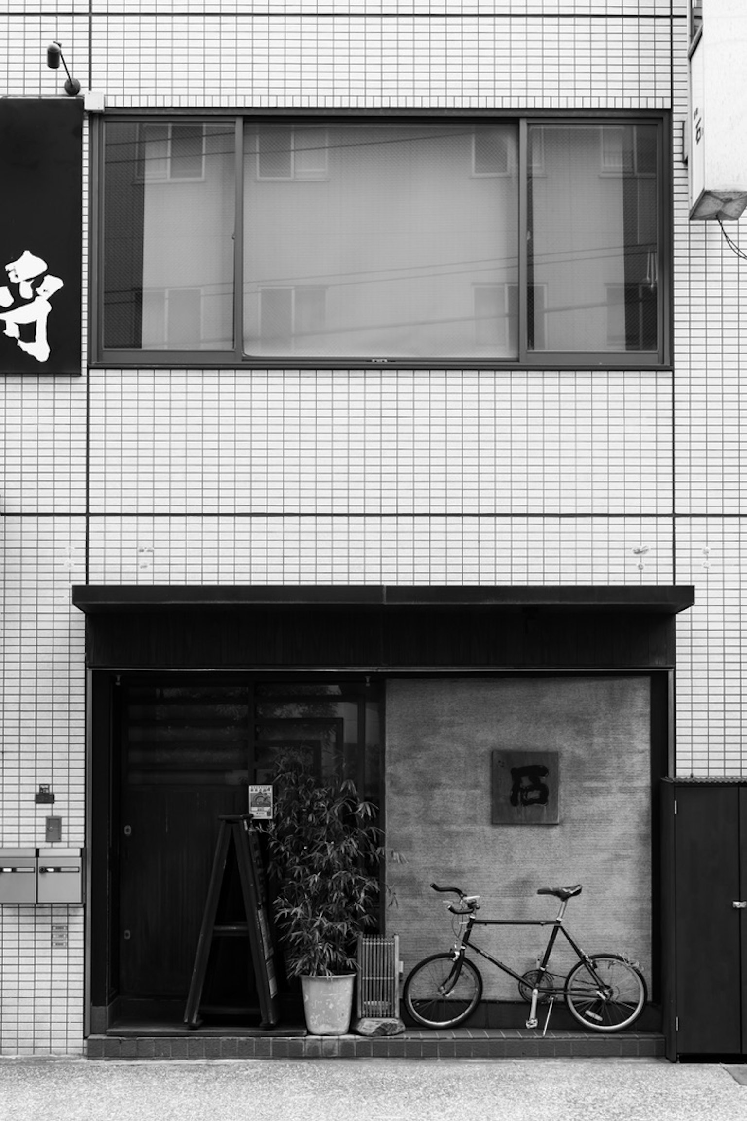 Fachada de edificio en blanco y negro con una bicicleta y plantas