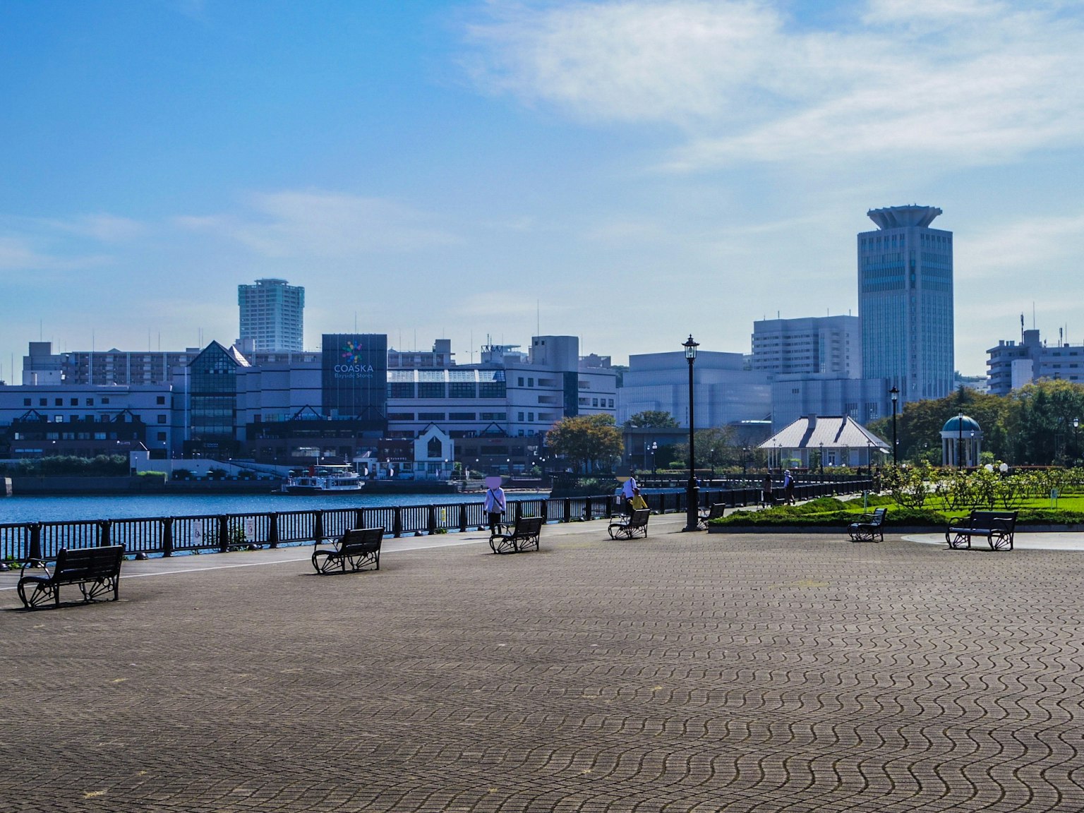 Vue du parc avec des bancs et la ligne d'horizon de la ville sous un ciel bleu clair