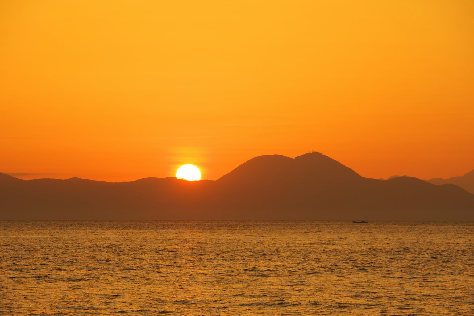 Beautiful orange seascape with the sun setting behind the mountains