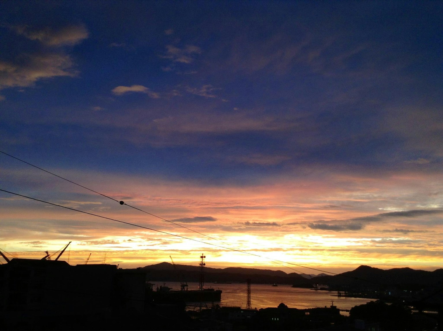 Cielo di tramonto vibrante sopra l'oceano con silhouette di colline