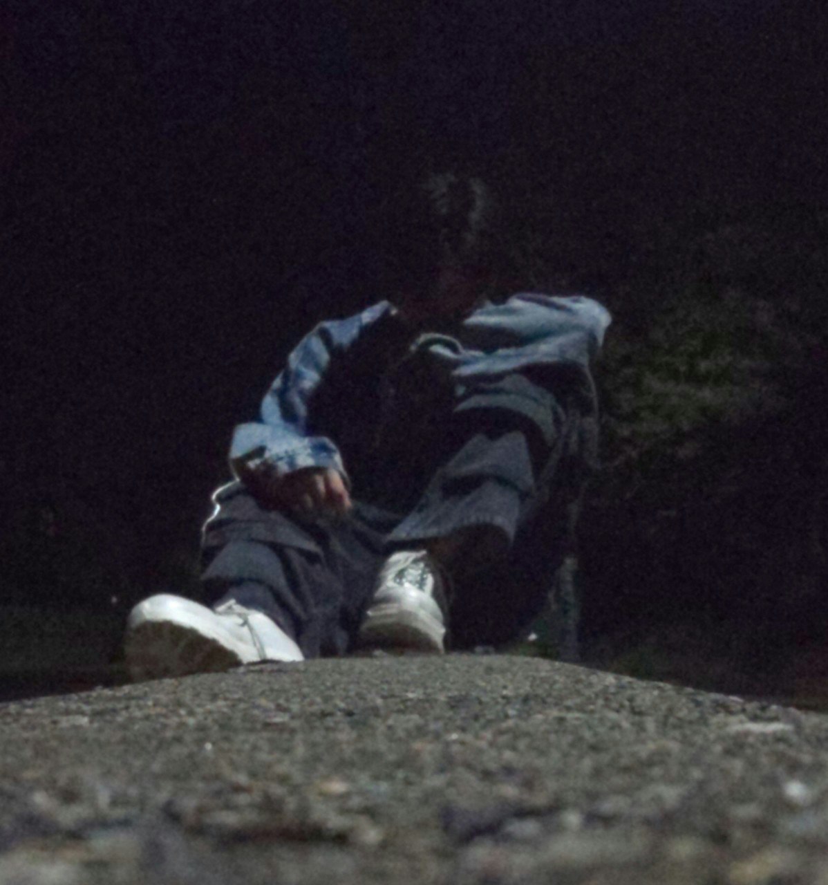 夜の岩場で座り込む人物