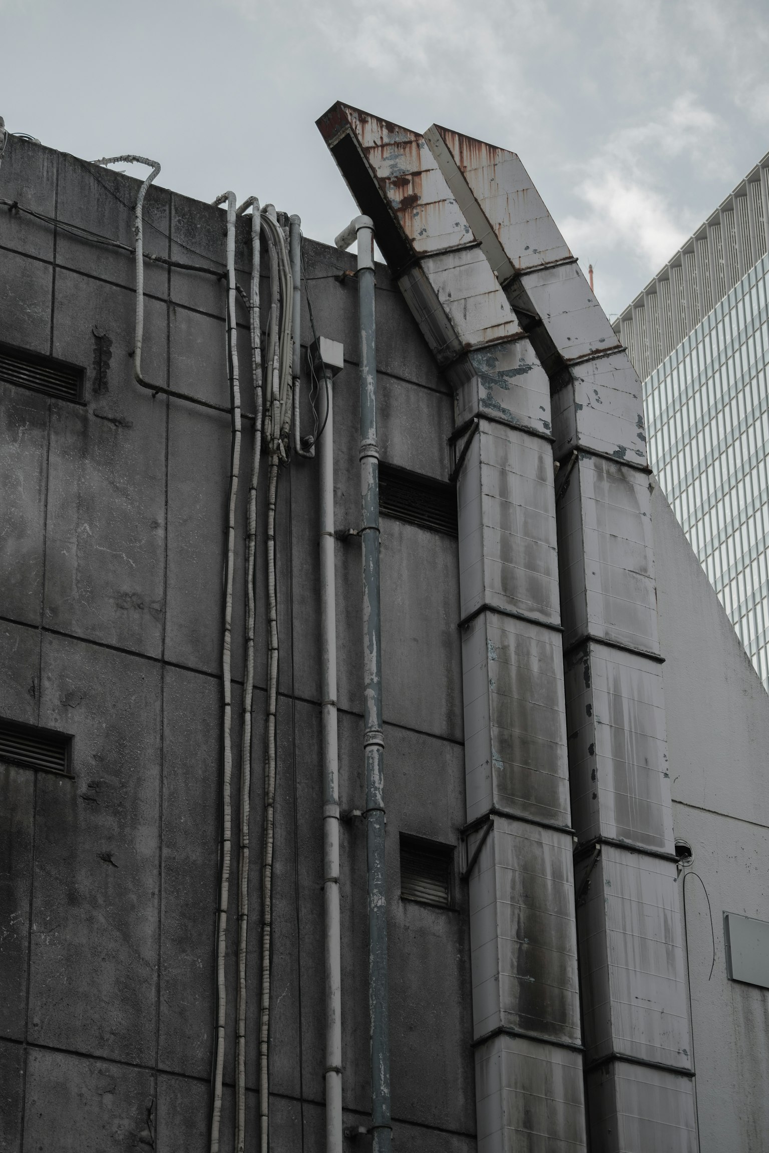 Dinding beton abu-abu dengan pipa dan elemen logam berkarat