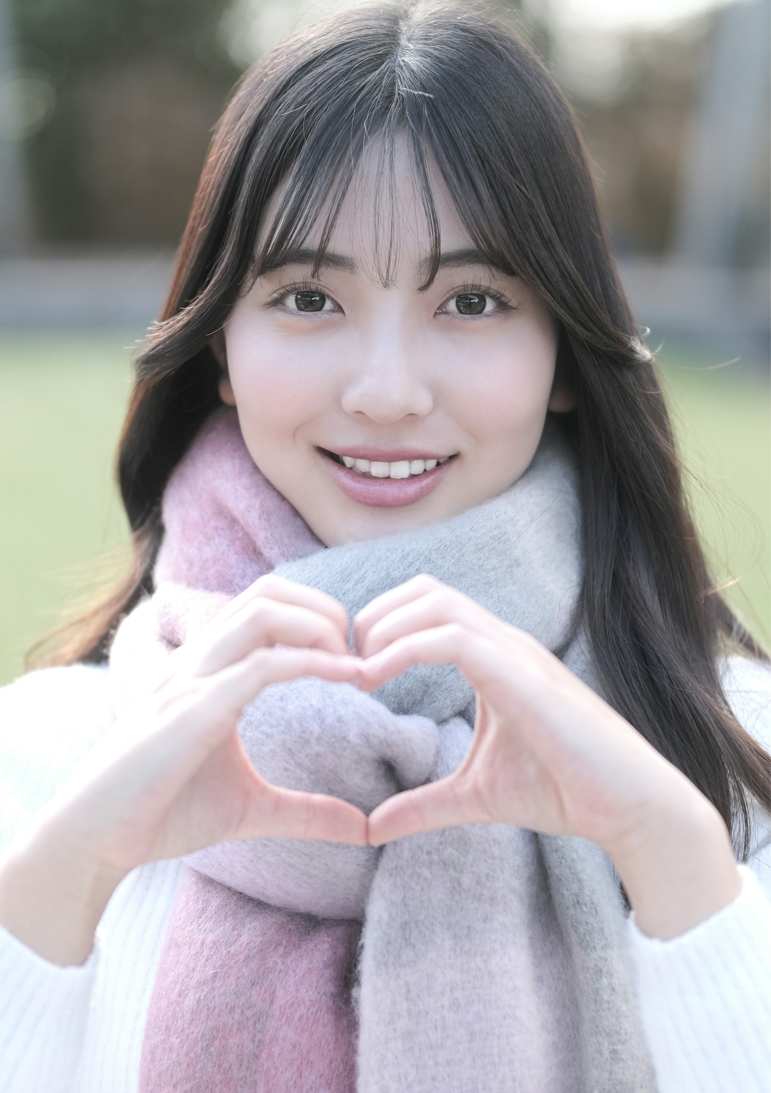 若い女性がハートの形を作って微笑んでいる写真