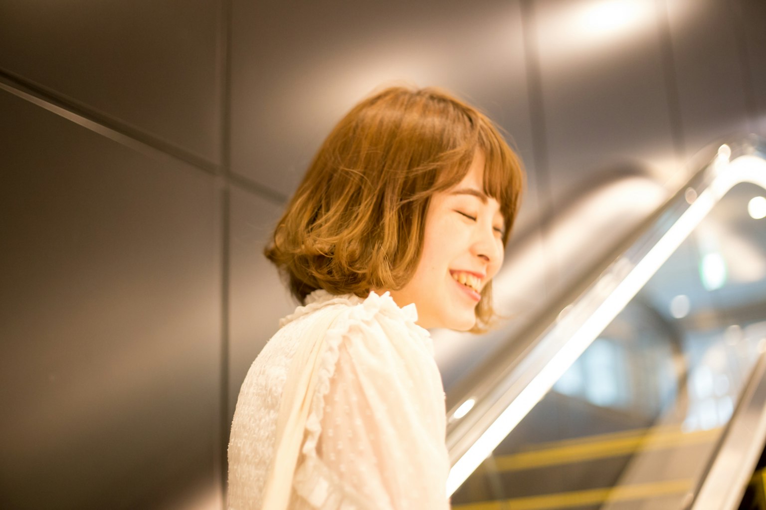 Una mujer sonriendo en una escalera mecánica