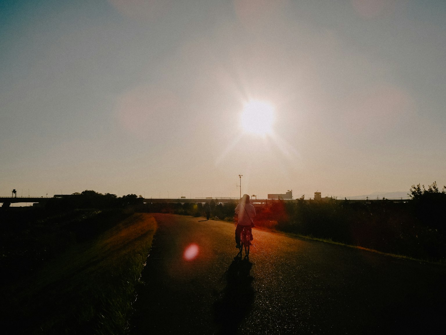 A person riding a bicycle with the sun setting in the background