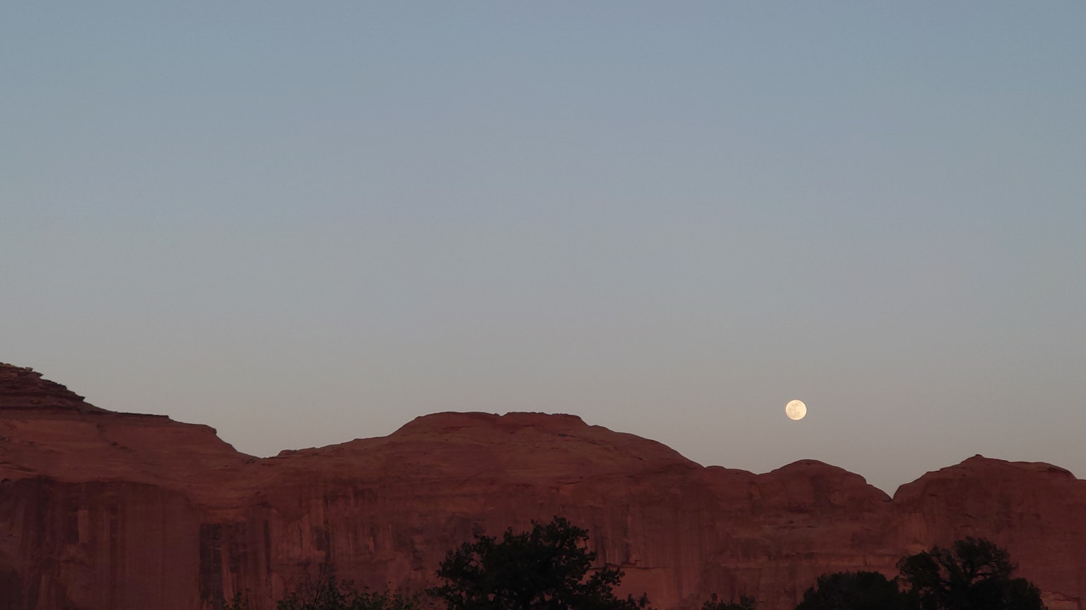 Paesaggio di montagne di roccia rossa con luna crescente e cielo crepuscolare