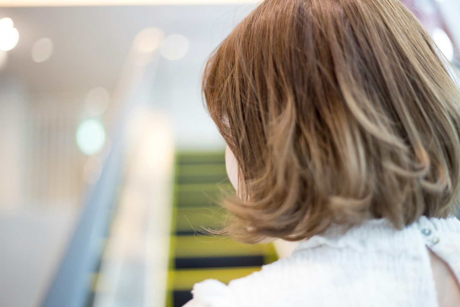 Una joven mujer subiendo escaleras con cabello castaño y una apariencia suave vistiendo una blusa blanca
