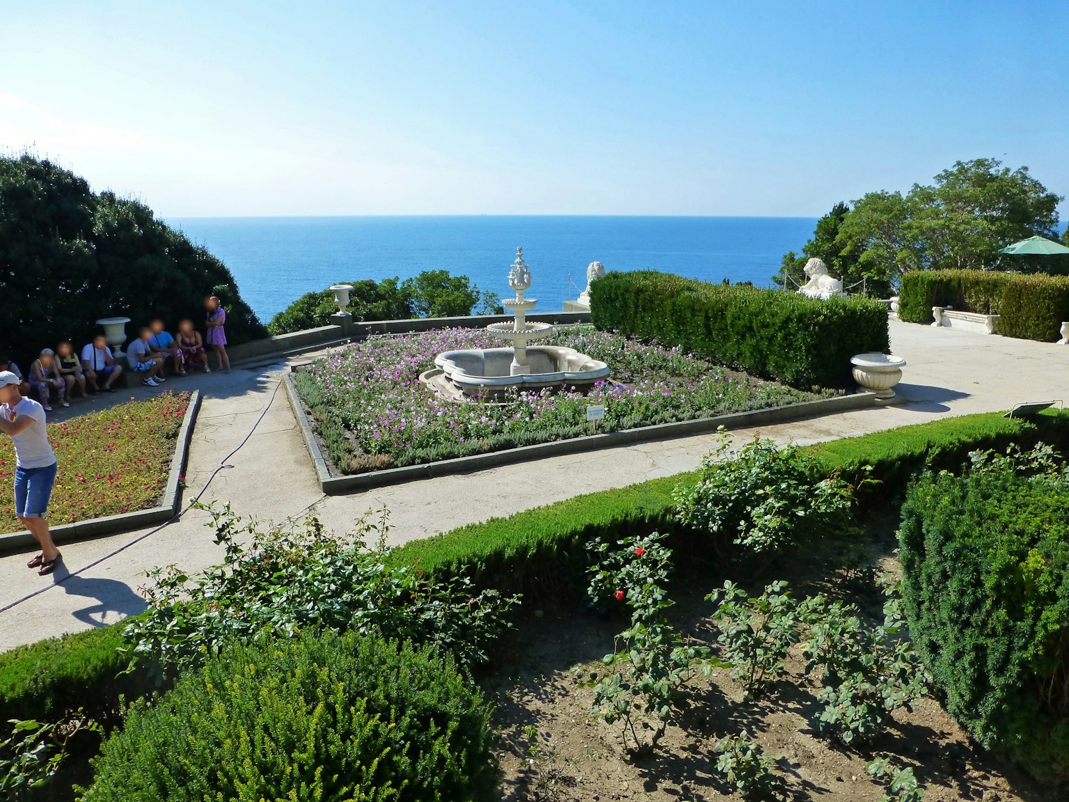 Schöner Garten mit Brunnen mit Blick auf das Meer mit Pflanzen und Besuchern