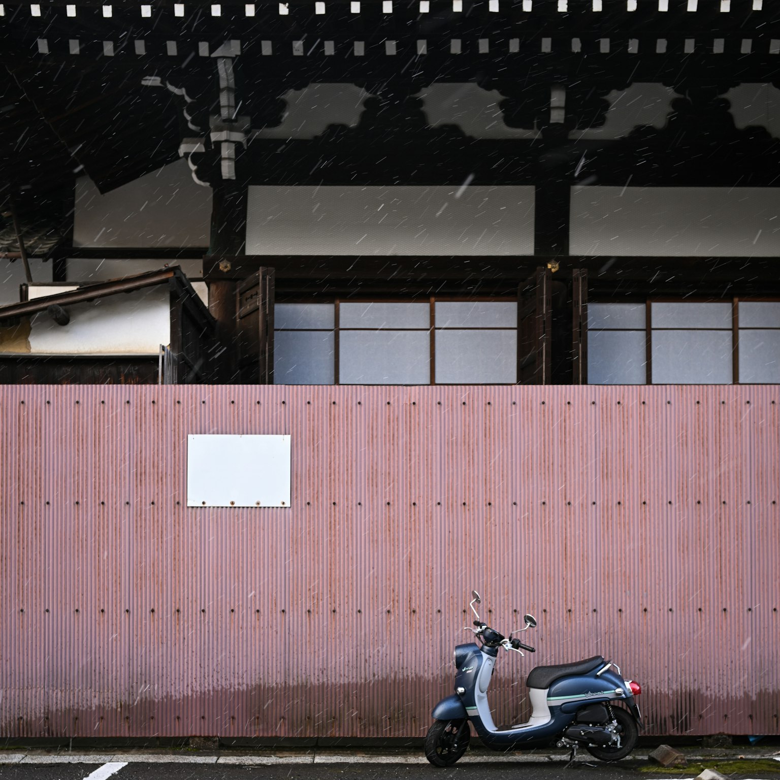 Altes japanisches Gebäude mit einer rosa Wand und einem Roller davor
