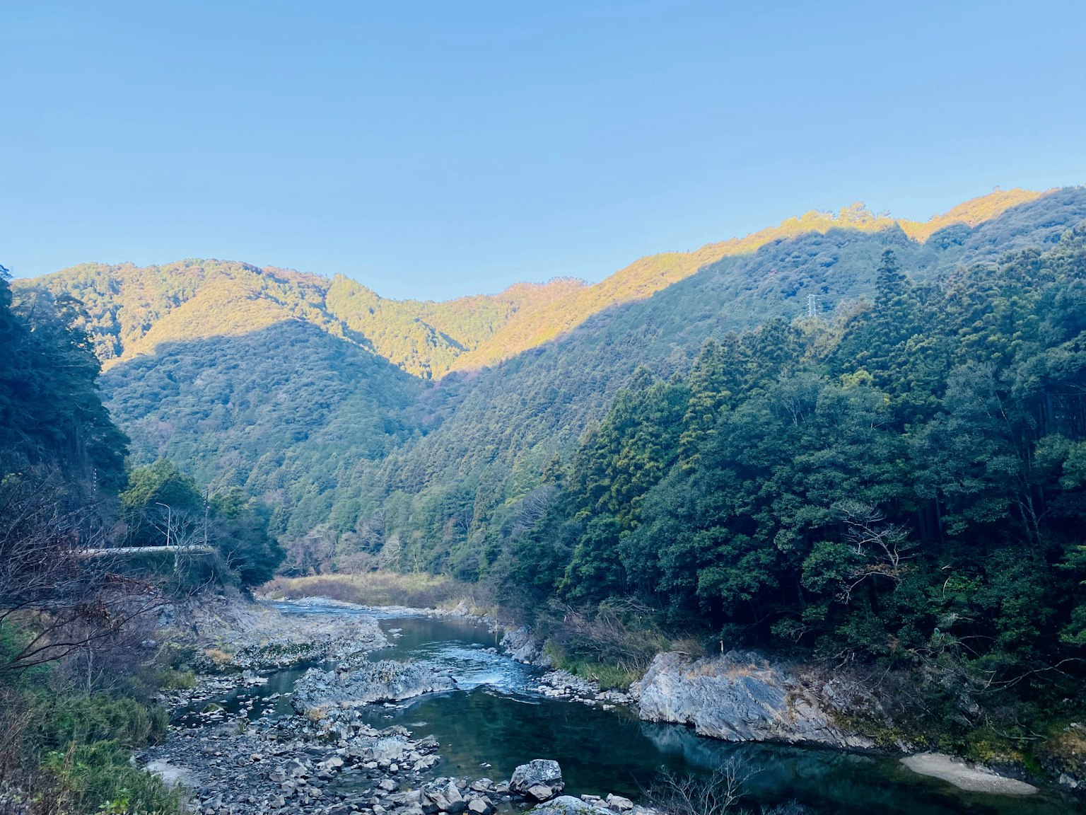 Paisaje de río sereno rodeado de montañas verdes y cielo azul