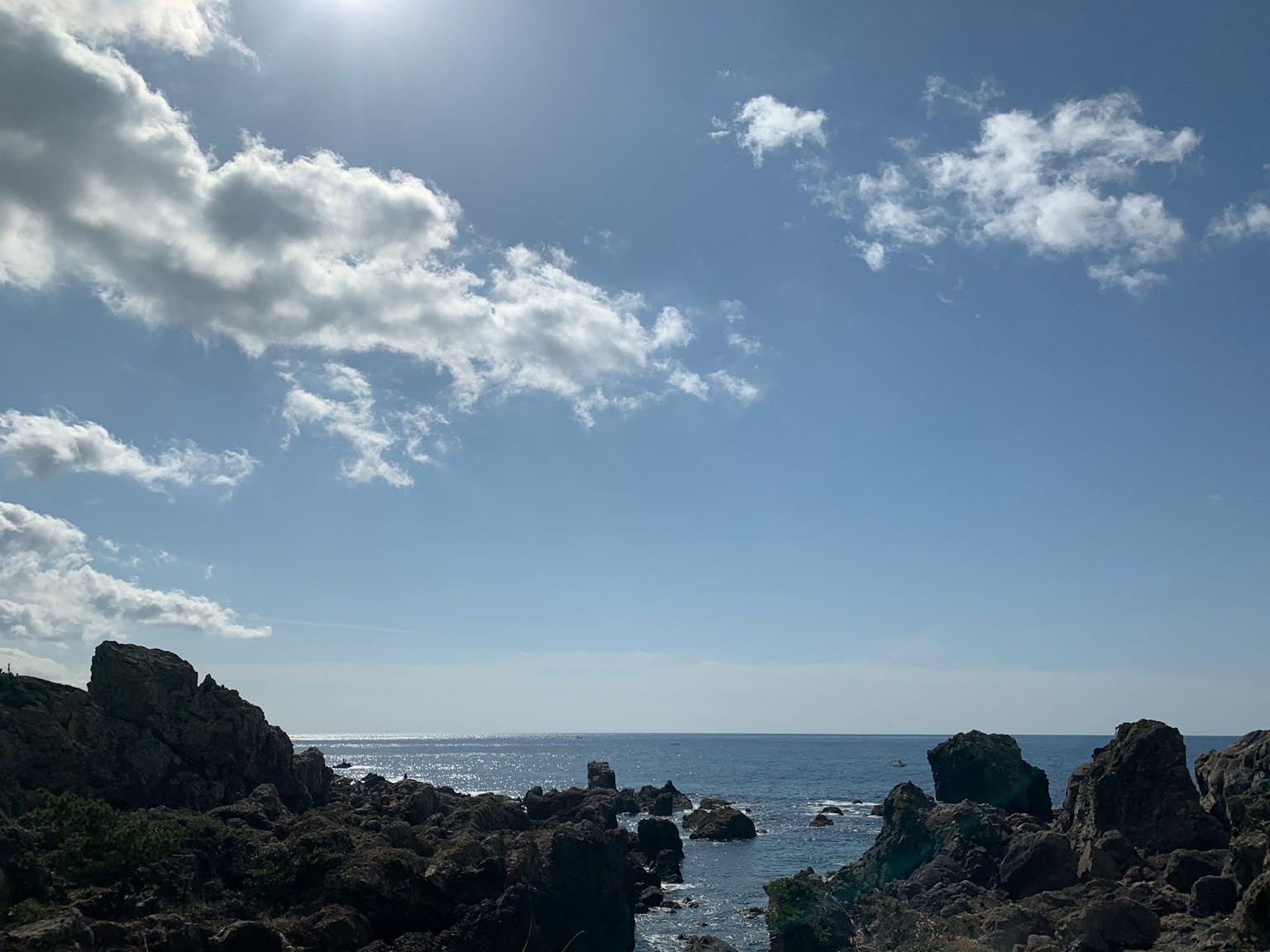 Pemandangan pantai dengan batu dan langit biru dengan awan putih