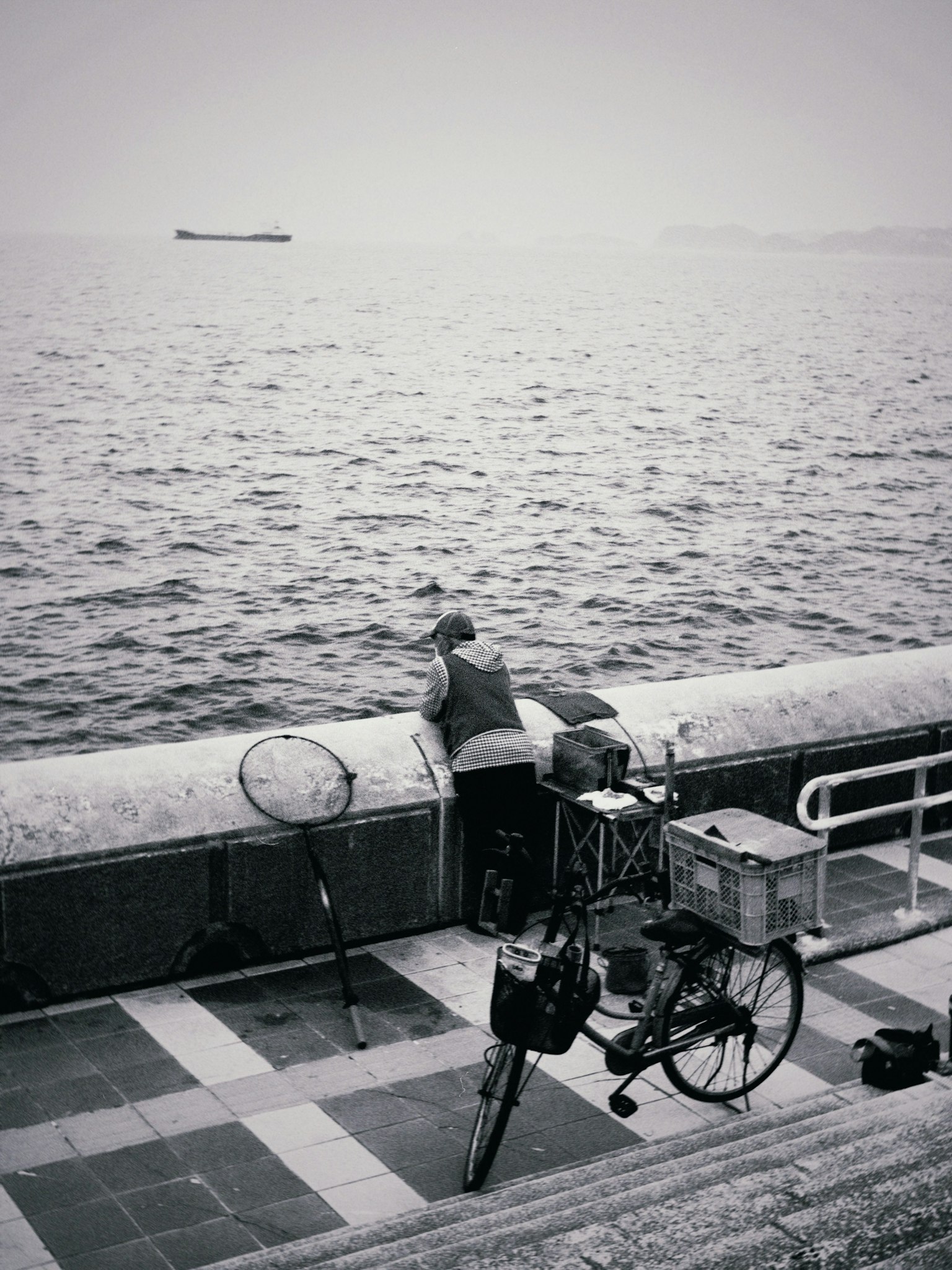 一个男人凝视海洋，旁边有一辆自行车