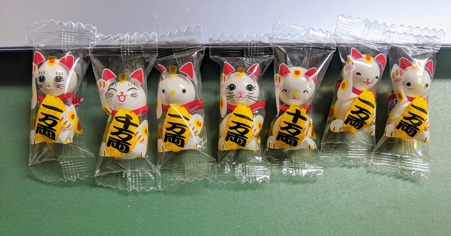 Sette figurine di Maneki-neko in un pacchetto di caramelle