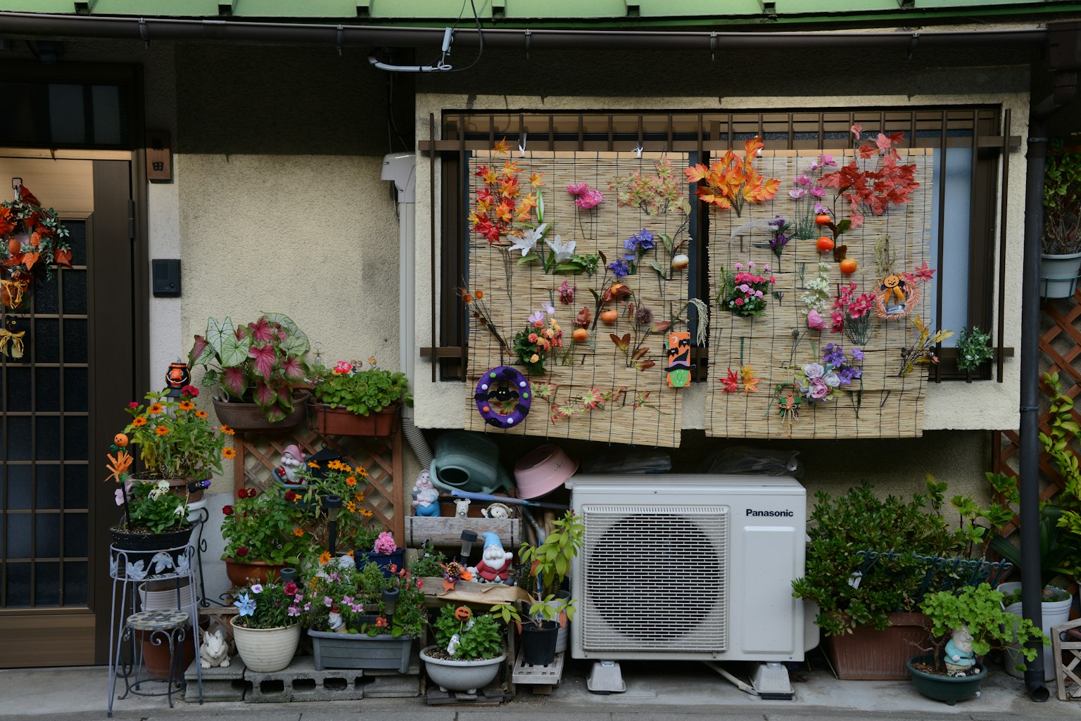 Exterior of a house adorned with colorful flowers and numerous potted plants