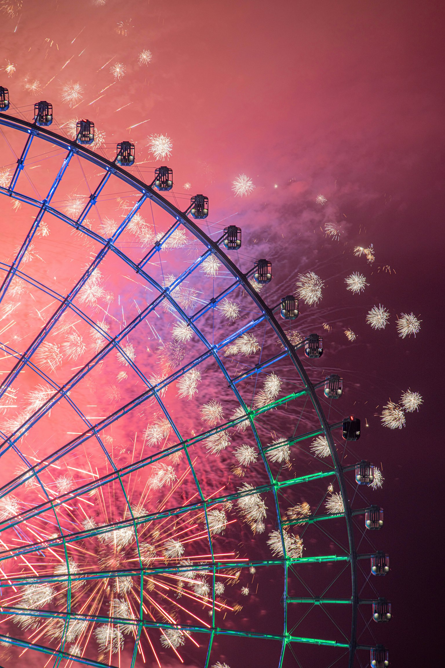 Contraste saisissant entre les feux d'artifice et la grande roue