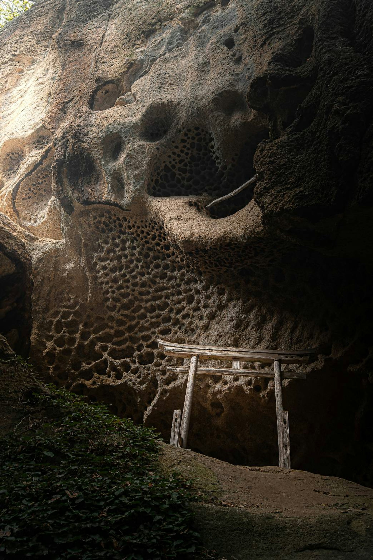Intérieur d'une grotte avec des motifs sculptés dans la roche et un torii blanc