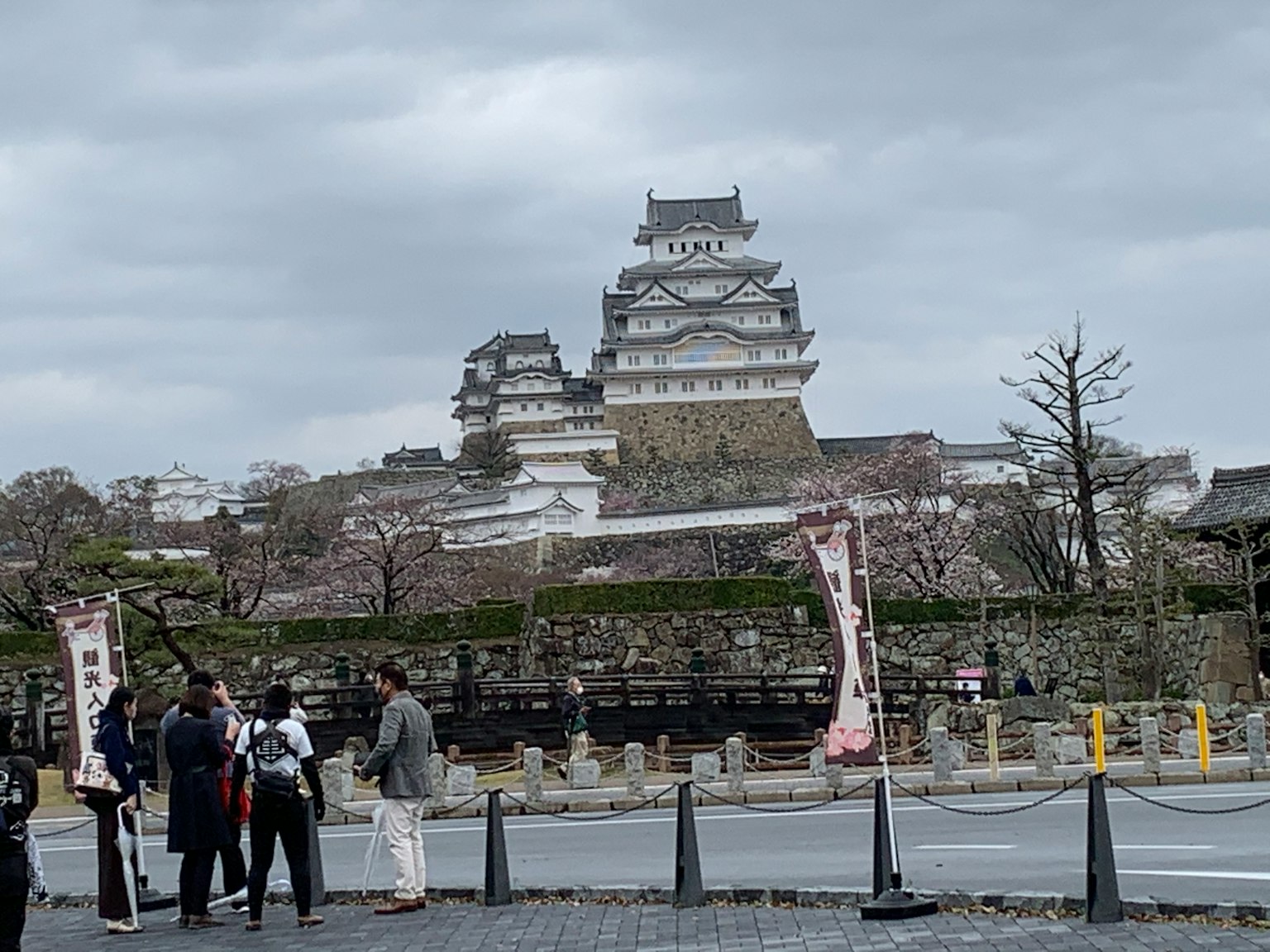 Wisatawan berdiri di dekat Kastil Himeji di bawah langit mendung