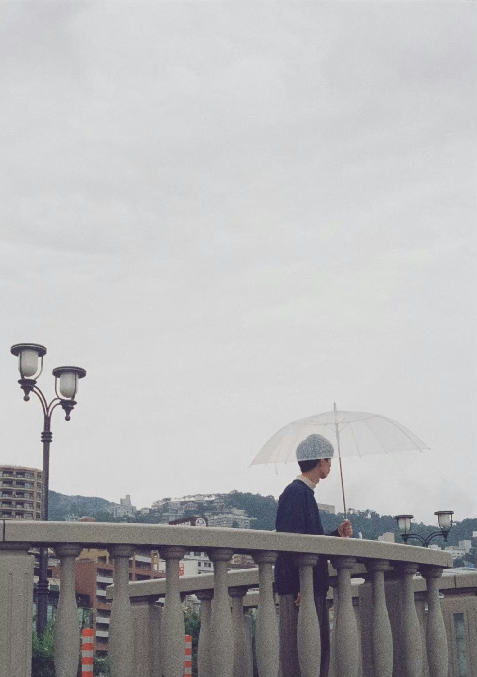 手持伞的人站在桥上