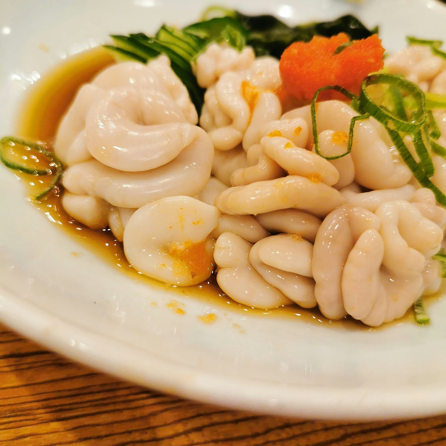 Un plato de mariscos blancos adornado con cebolla verde y huevas rojas