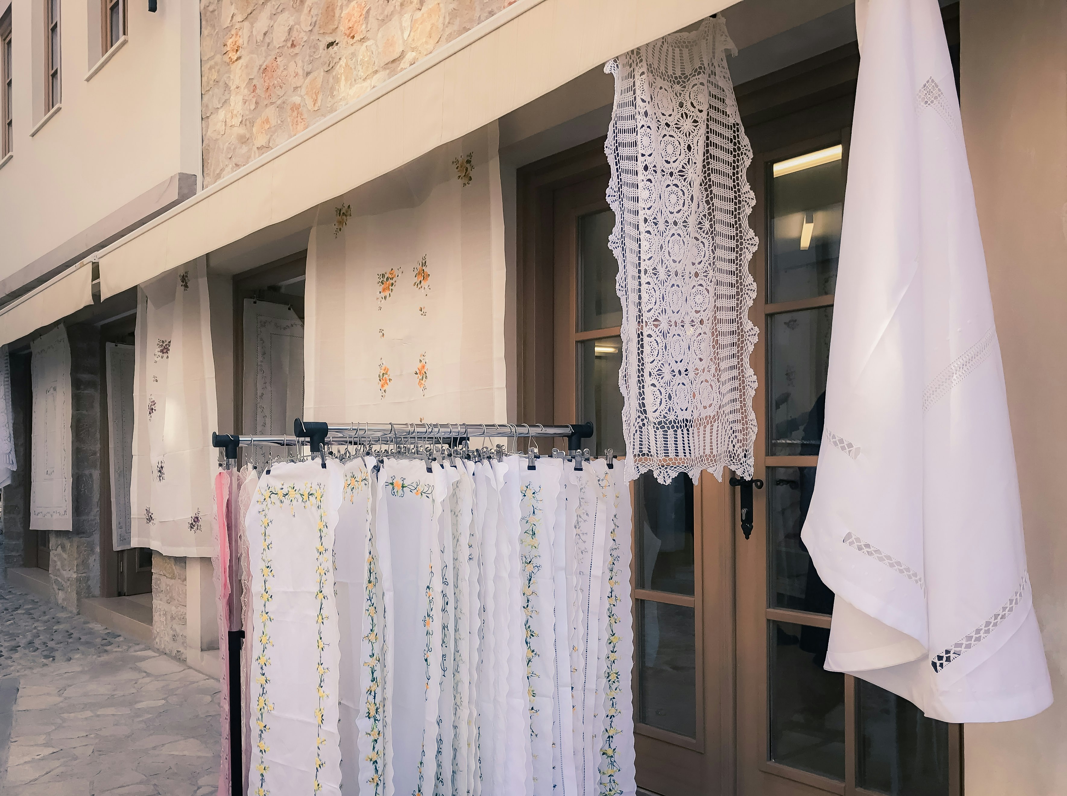 storefront display of white lace curtains along a narrow alley