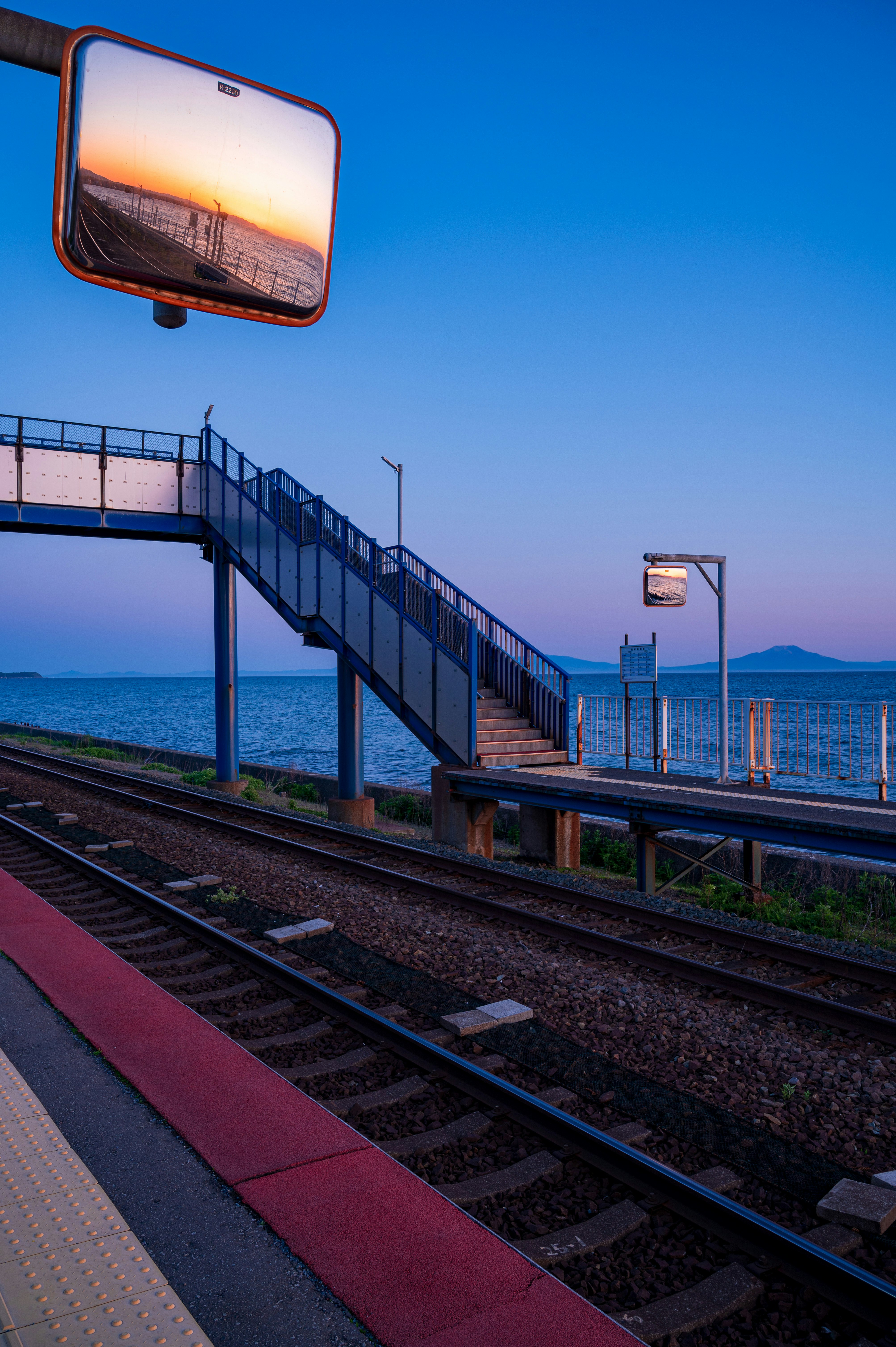 train tracks and platform by the sea at dusk