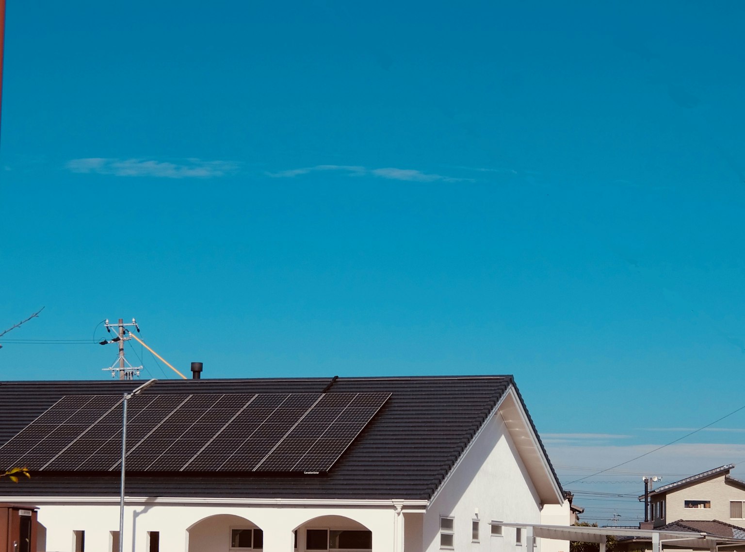Una casa bianca con pannelli solari sotto un cielo blu
