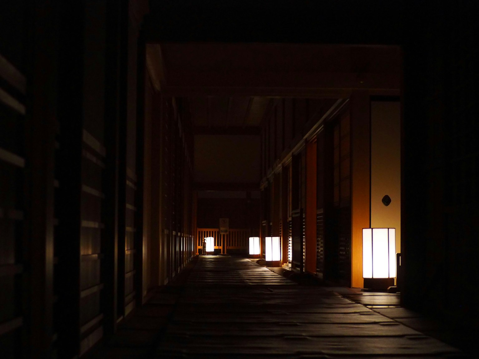 Dimly lit corridor with traditional Japanese lanterns casting warm light