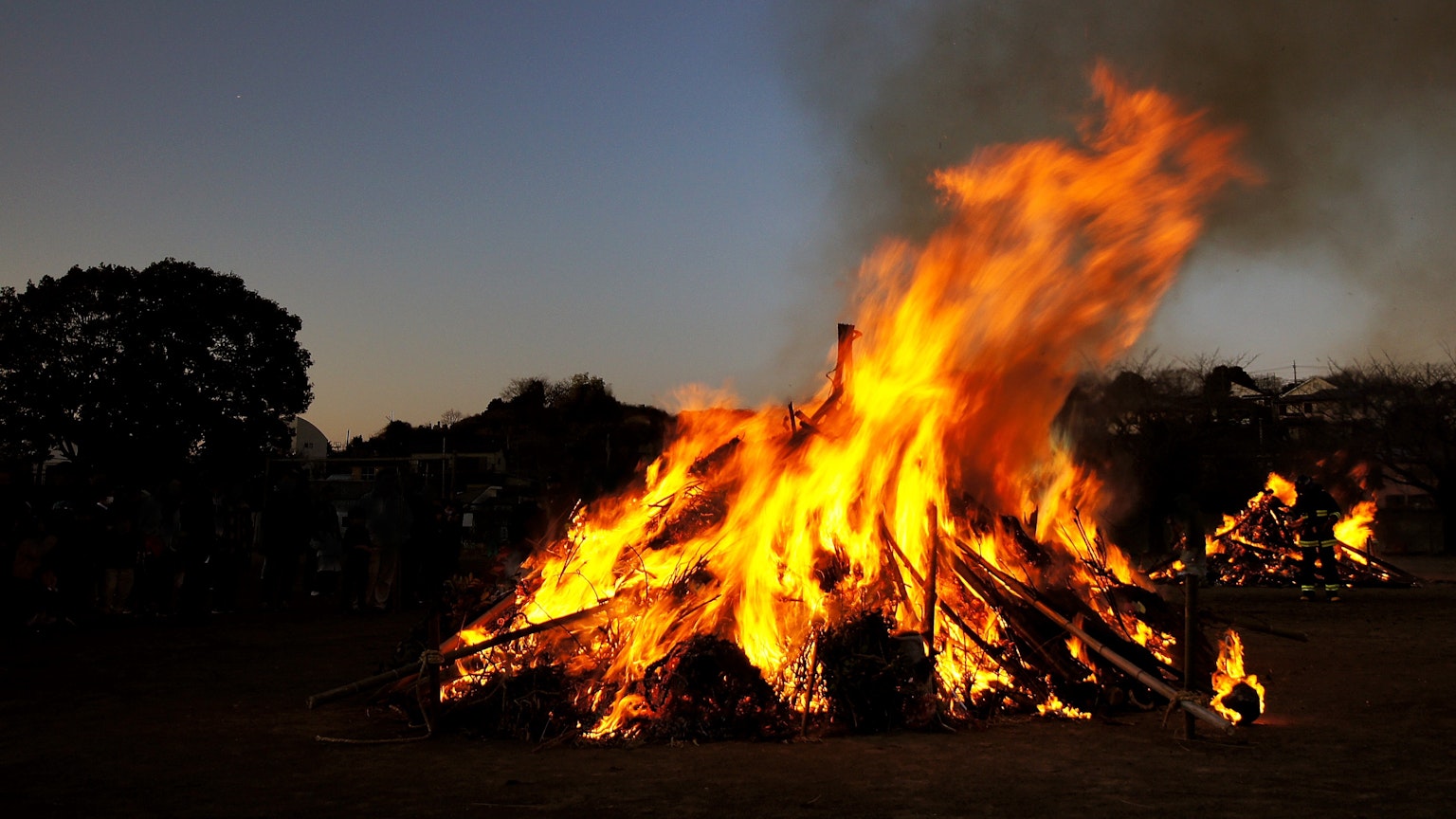 A large bonfire with bright flames against a twilight sky