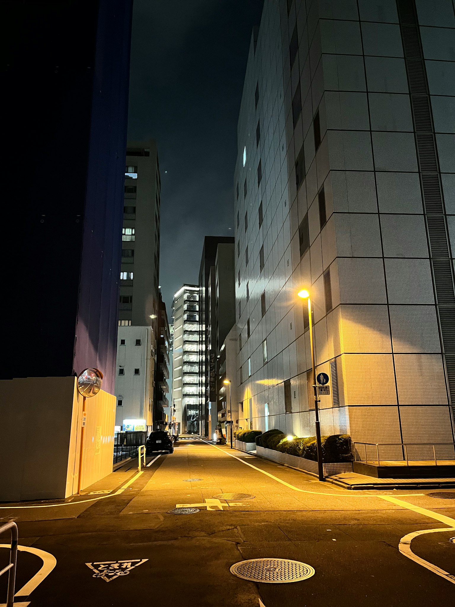 Calle estrecha entre edificios de noche iluminada por farolas
