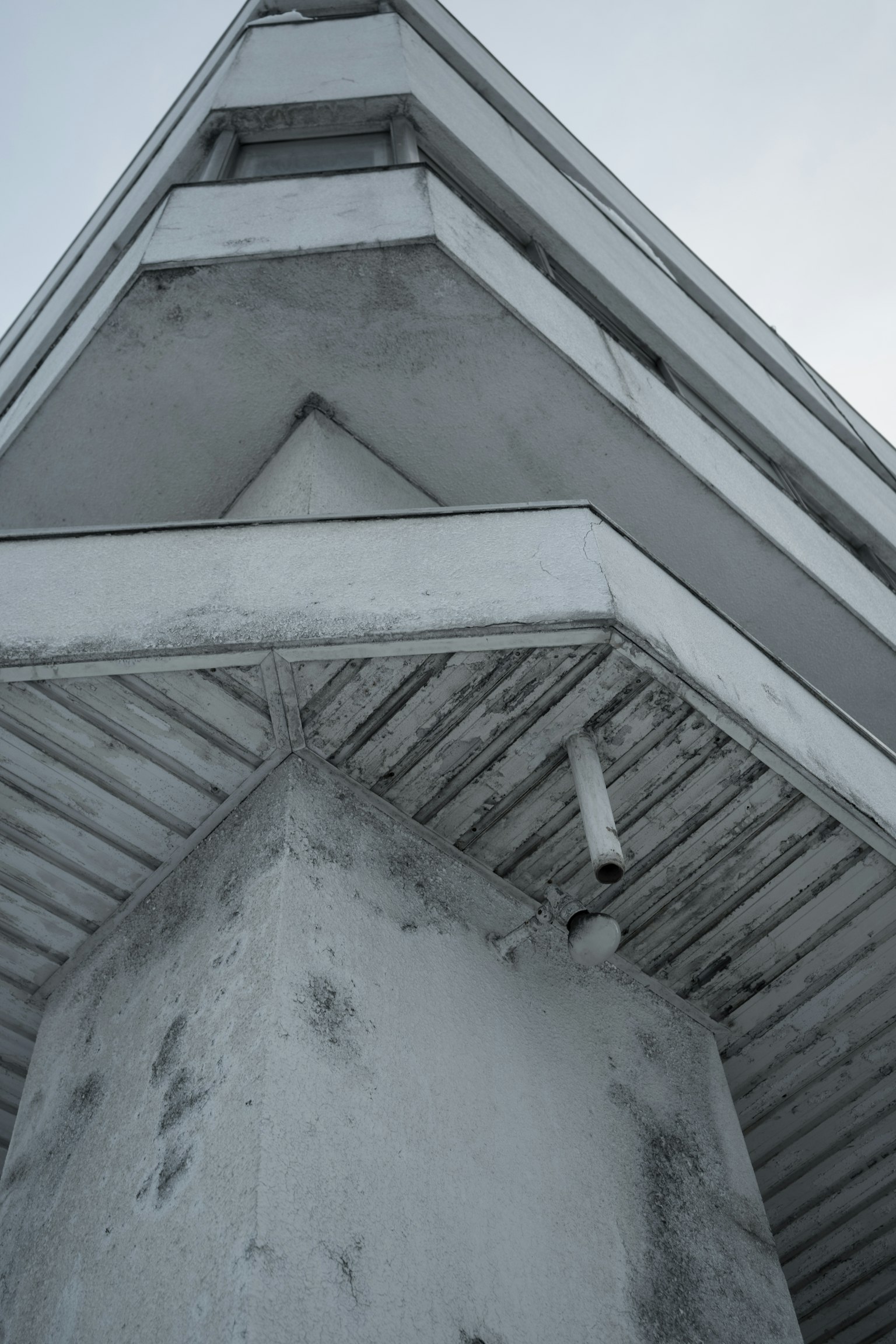 Vue d'un coin de bâtiment blanc de dessous avec un toit triangulaire distinctif et des caractéristiques structurelles