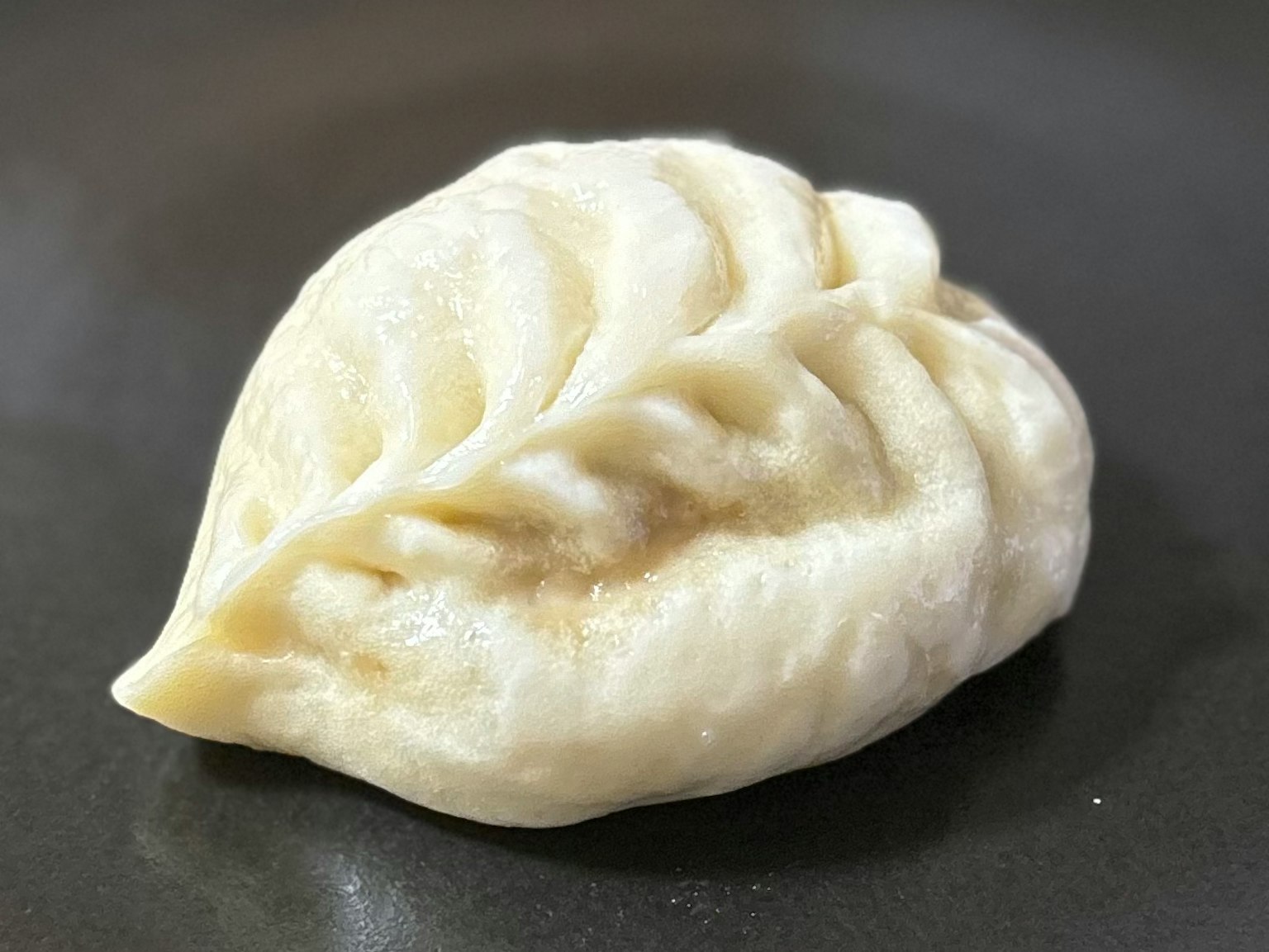 一個白色的餃子，形狀像葉子，放在盤子上