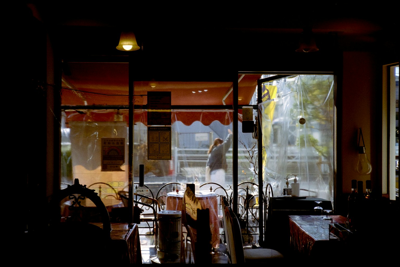 View from inside a café looking out through the window with a person and tables visible