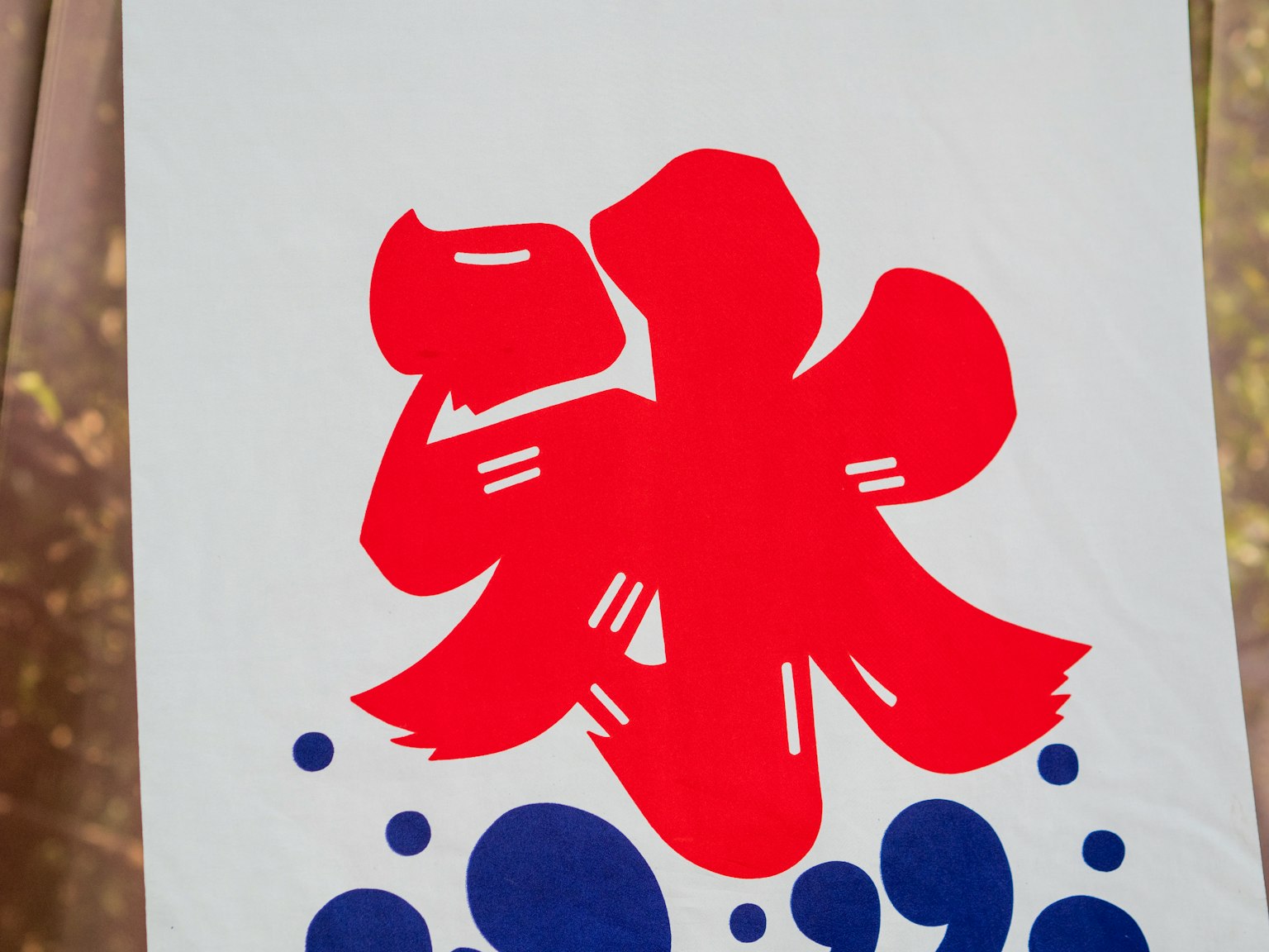 一面白色布料的橫幅，上面用紅色字母寫著‘冰’字，配有藍色圓形圖案