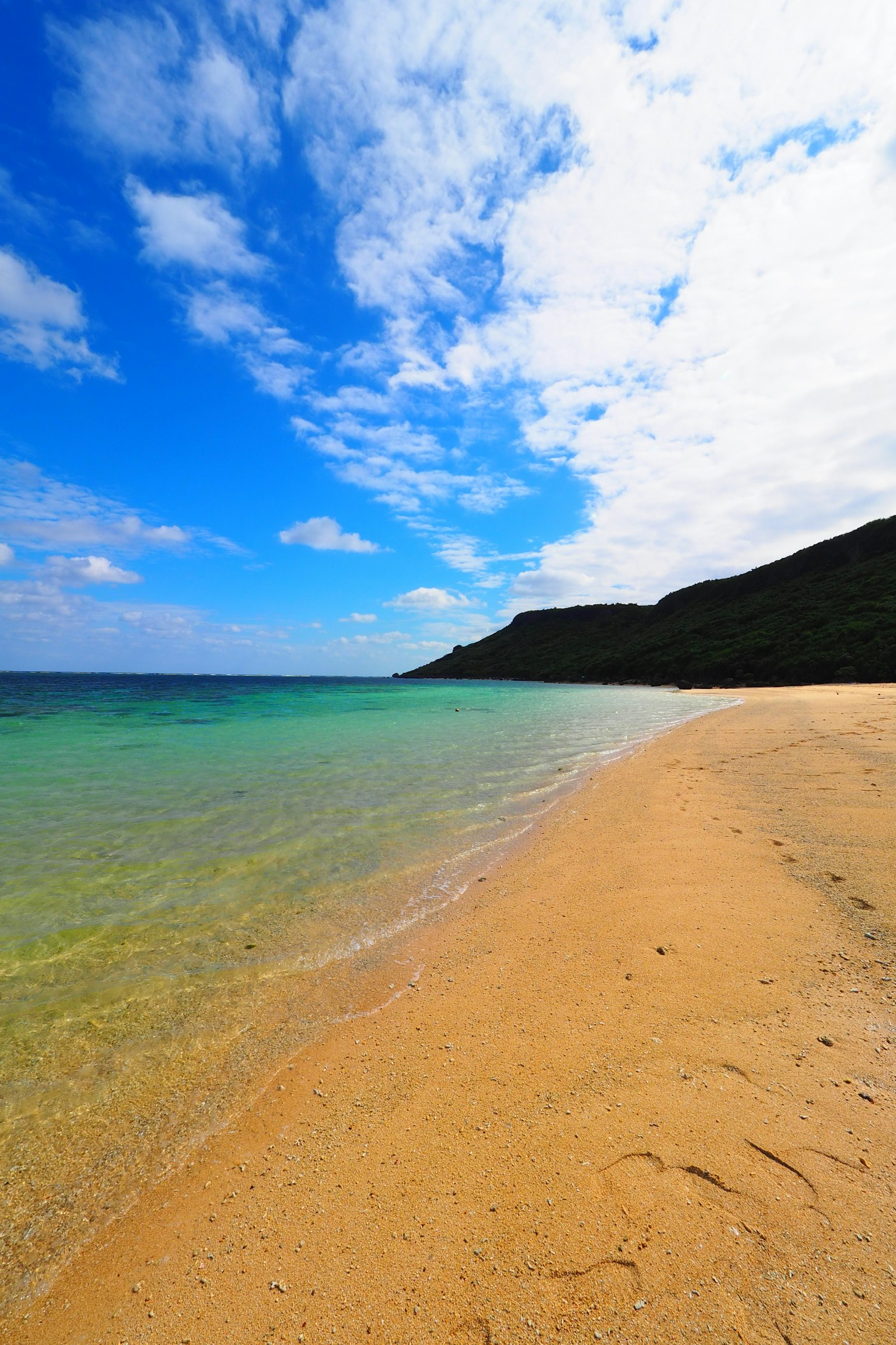 Pemandangan pantai yang indah, langit biru dan awan, laut jernih, pantai berpasir