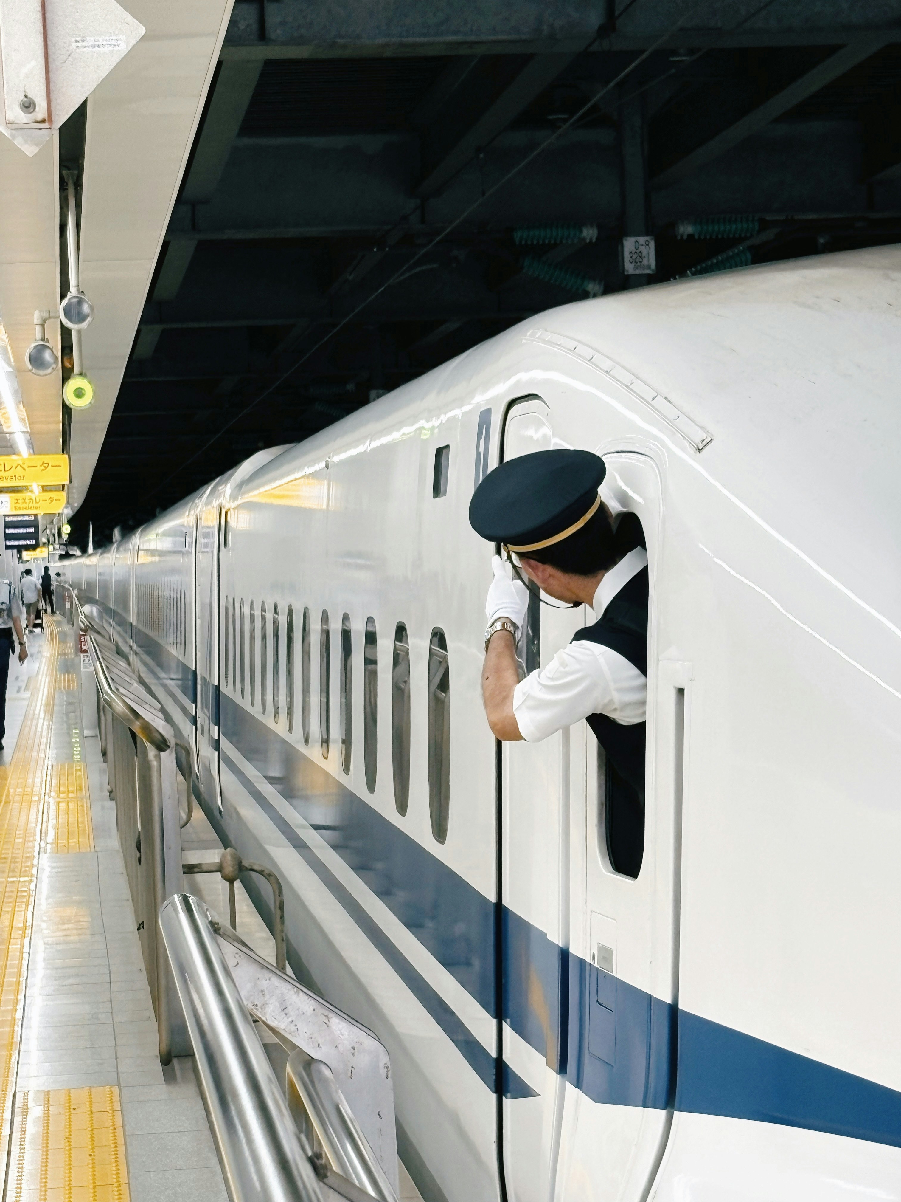 white high-speed train stopped at a station platform with staff