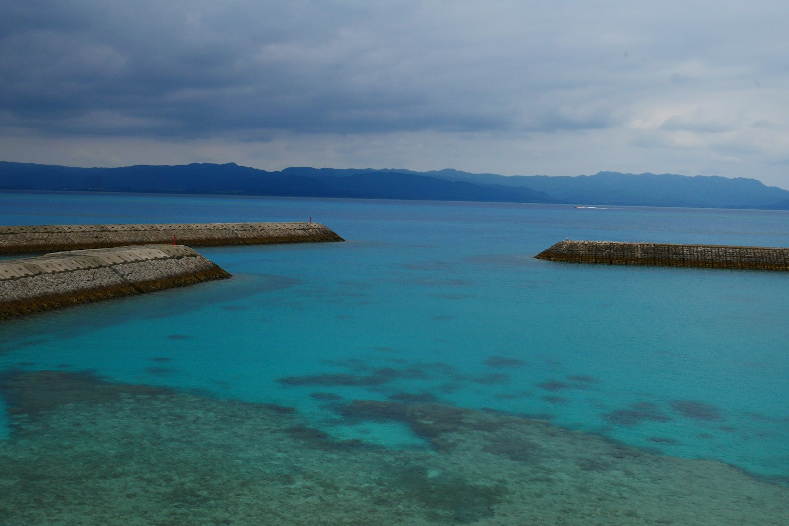 Vaste mer turquoise sous un ciel nuageux avec des montagnes lointaines