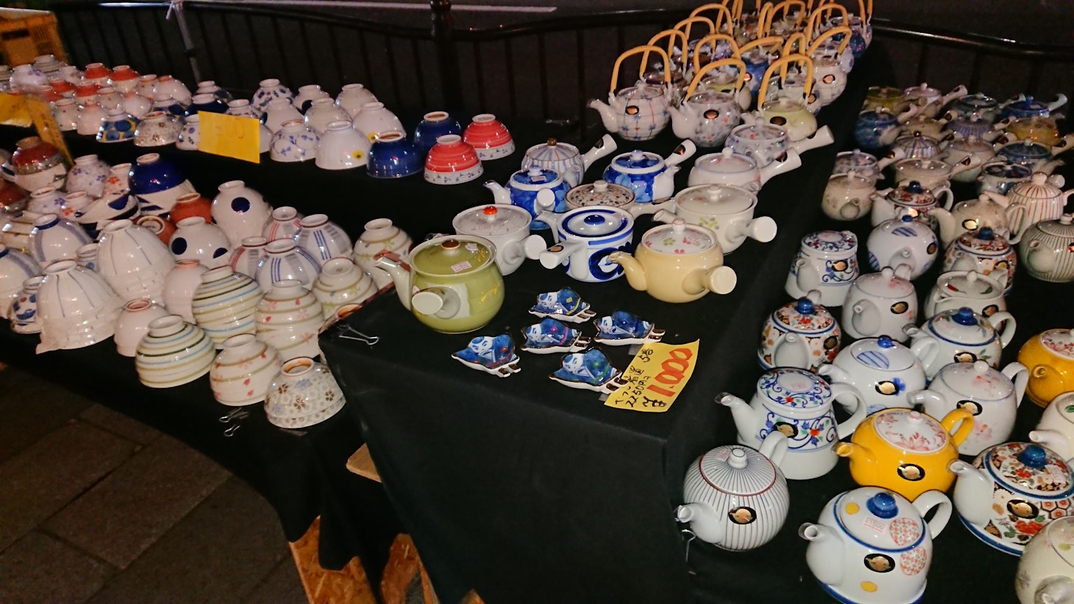 Una variedad de teteras y tazas de cerámica exhibidas en un mercado