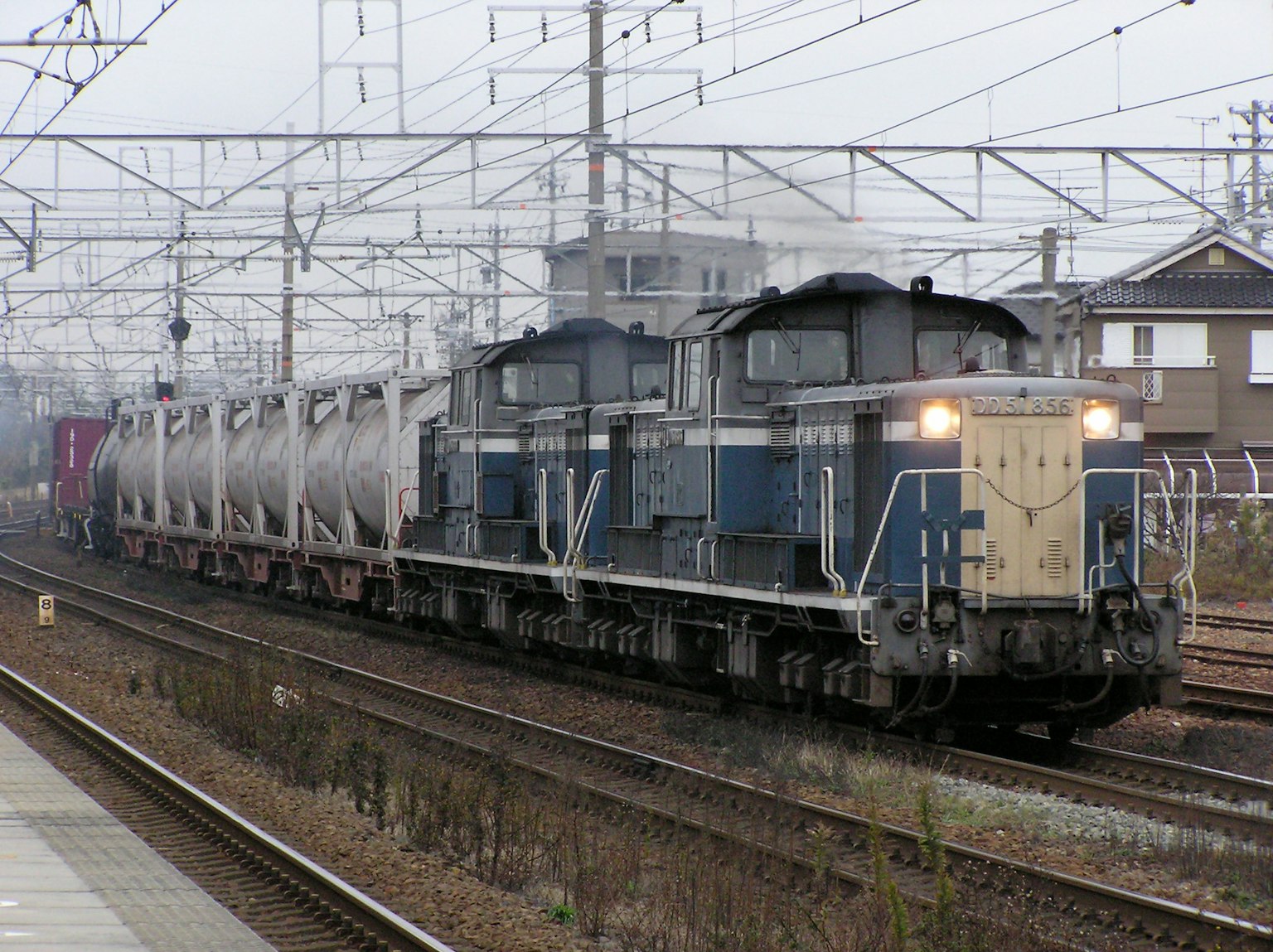 Tren de carga azul y blanco pasando por una estación